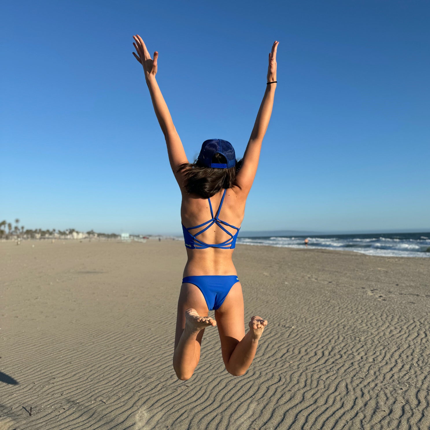 Cross back adjustable straps of a sport bikini with bra style top. Sapphire blue straps and matisse or talavera tile style print. Sportsbra-like top for beach volleyball and surfing. Reverses to solid blue.
