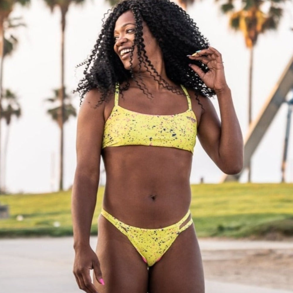 African american girl skateboarding in Venice beach in lime colored bikini made by Pitviper and Pepper Swimwear.
