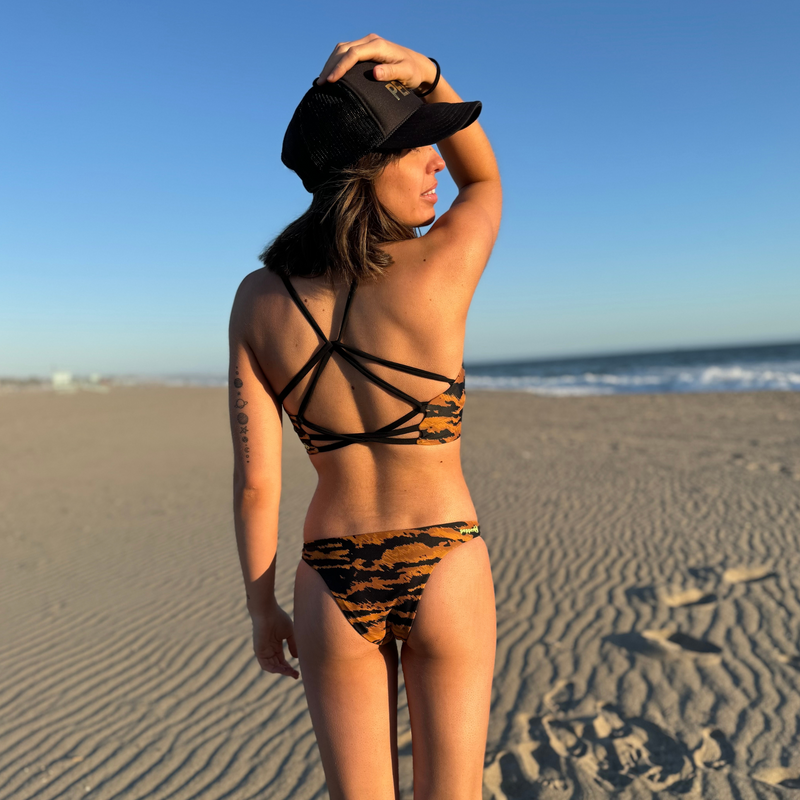 Cross back adjustable straps of a sport bikini with bra style top. Black straps and copper brown tiger print. Sportsbra-like top for beach volleyball and surfing. Reverses to a custom cosmic stars and moon Pepper Swimwear print.