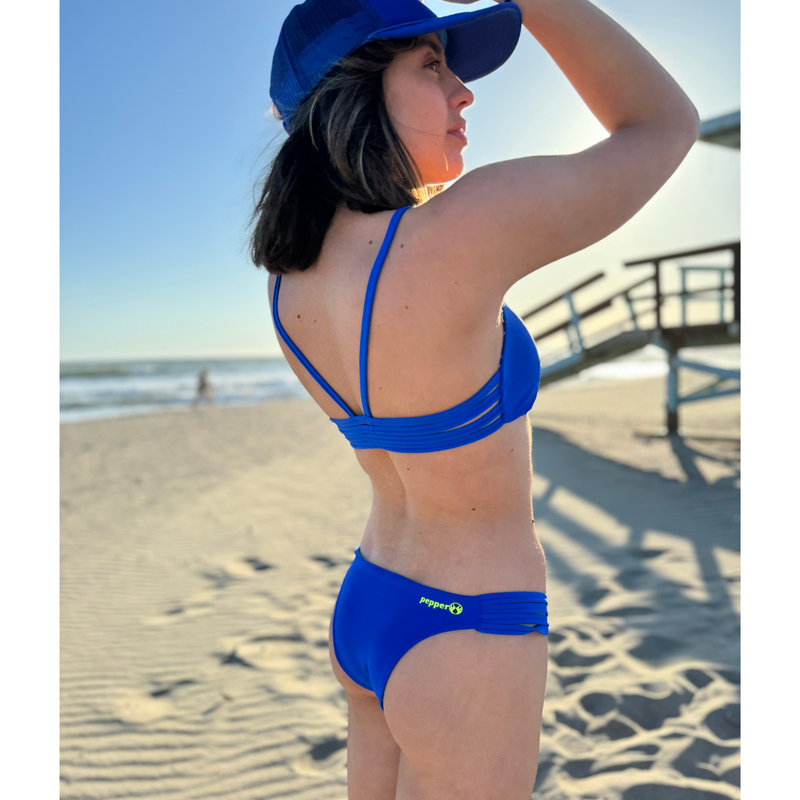 Reversible sport bikini bottom with four strap inserts at hip.  Mid rise with medium back coverage. Solid sapphire blue reverses to a matisse inspired or talavera tile style print. Comfortable for sporty athletic girls and women, great for beach volleyball and surfing. Pepper Swimwear.