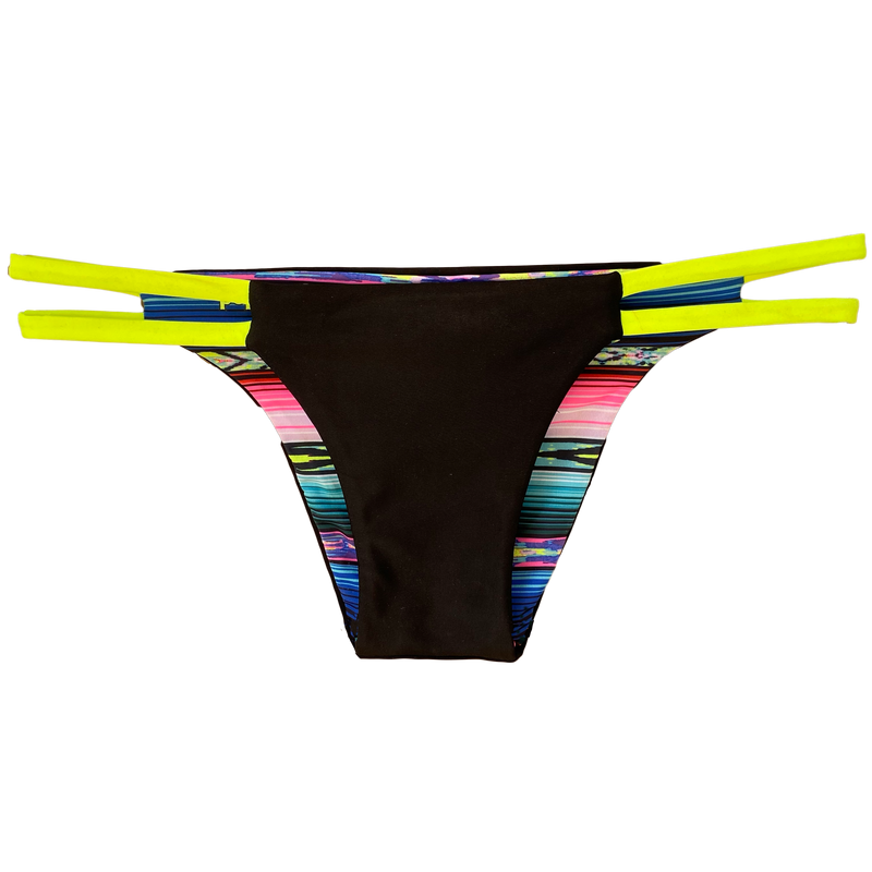 An attractive and stylish reversible sport bikini bottom featuring a solid black fabric with two neon yellow colored straps on both hips; reverses to a colorful Mexican blanket serape print.